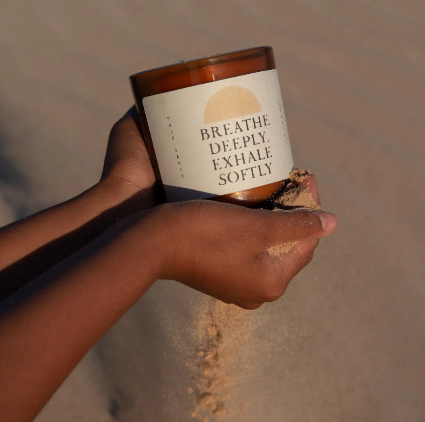 Person holding the Etikette Breathe Deeply Candle - Palo Santo in sand