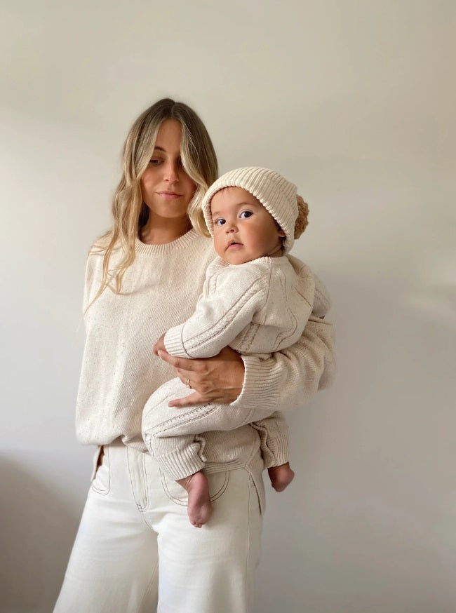 Person holding a baby wearing the Classic Knit Romper Biscotti Fleck by Ziggy Lou