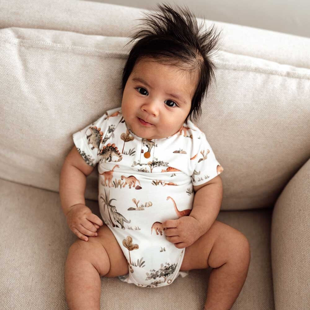 Baby on couch wearing Dino Short Sleeve Organic Bodysuit