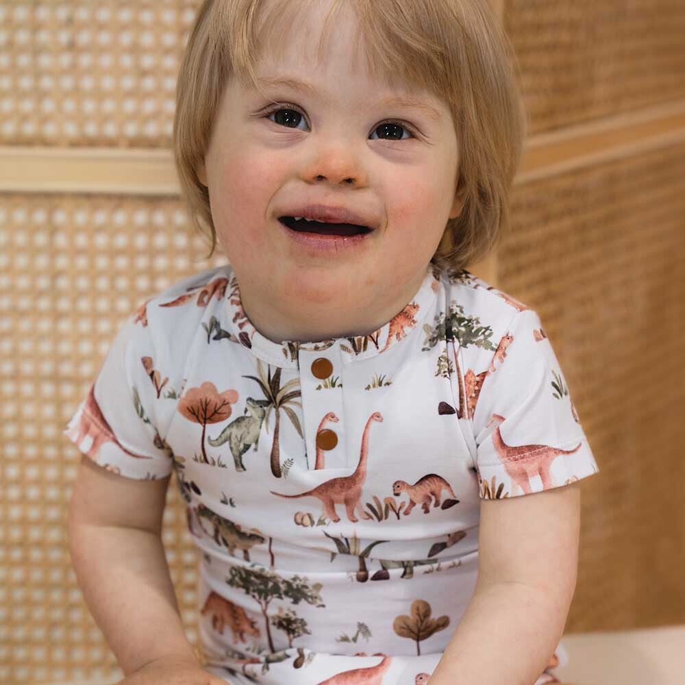 Toddler smiling wearing the Dino Short Sleeve Organic Bodysuit by Snuggle Hunny