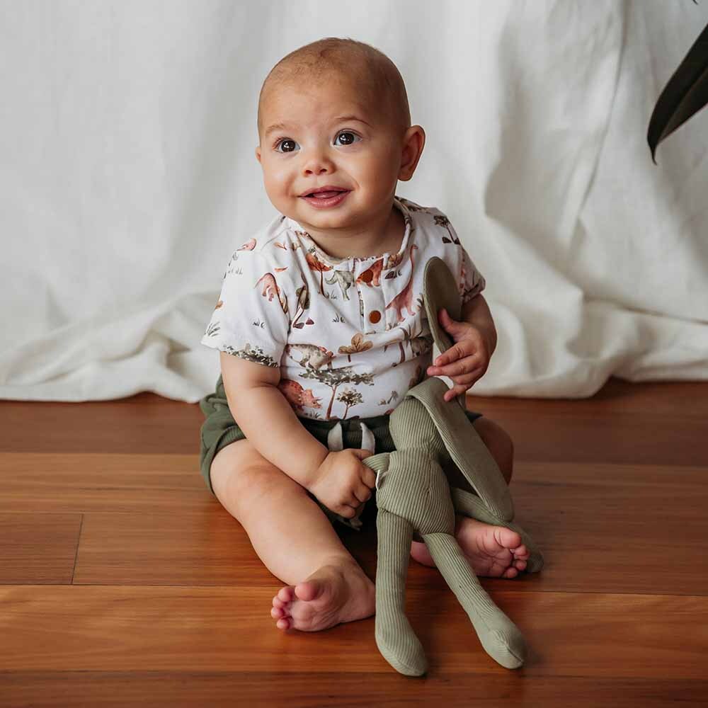 Toddler smiling wearing the Dino Short Sleeve Organic Bodysuit by Snuggle Hunny