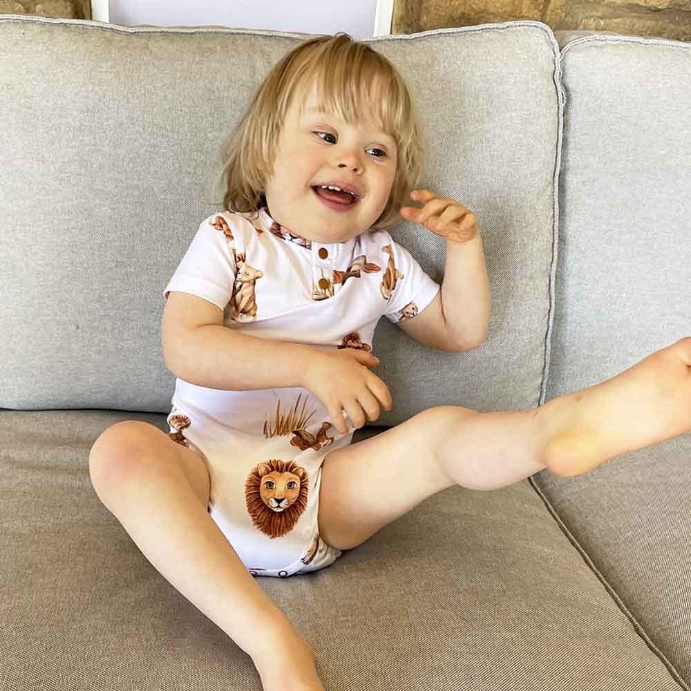 Toddler on couch wearing Lion Short Sleeve Organic Bodysuit by Snuggle Bunny
