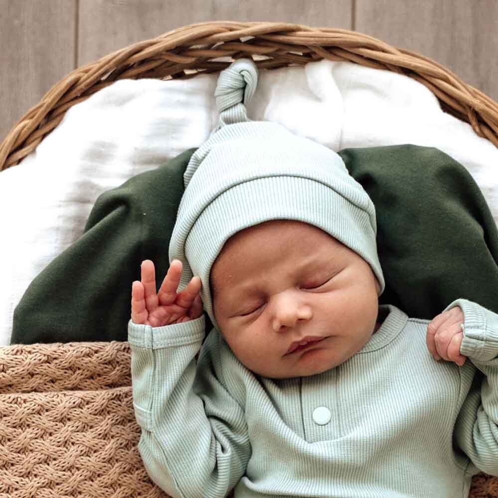 Baby asleep wearing the Sage Ribbed Organic Knotted Beanie by Snuggle Hunny
