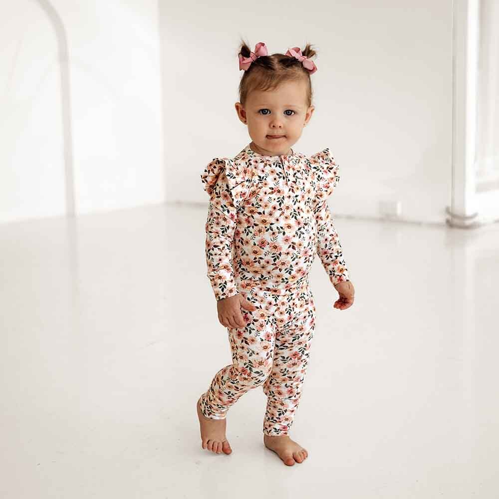 Toddler walking wearing the spring floral organic growsuit by Snuggle Hunny