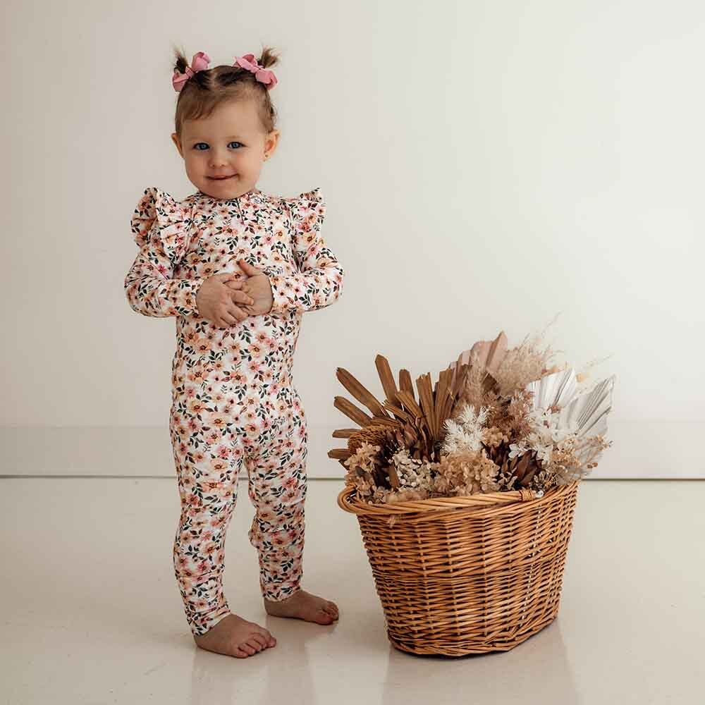 Toddler standing wearing the spring floral organic growsuit by Snuggle Hunny