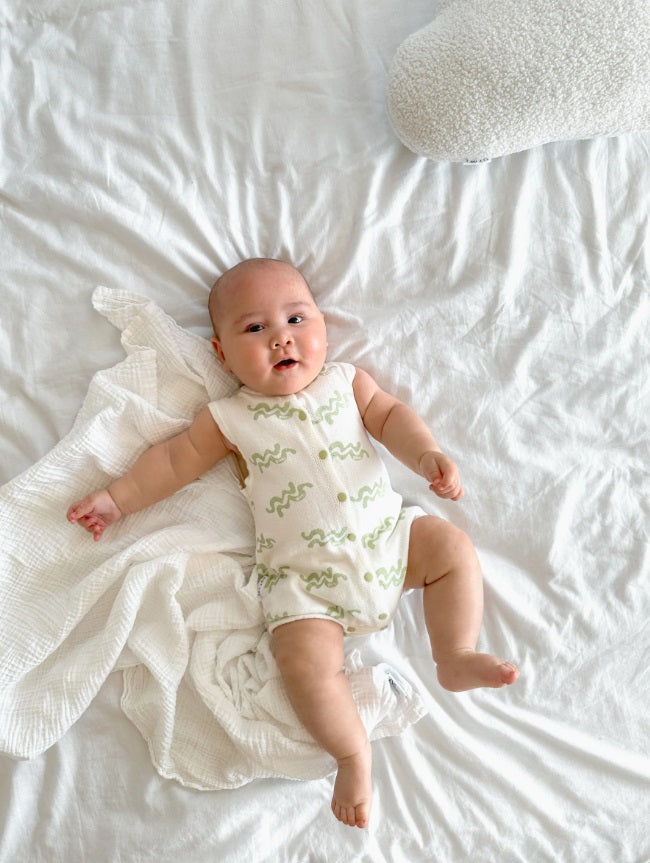 Baby in bed wearing the Summer Bubble Romper Waves by Ziggy Lou