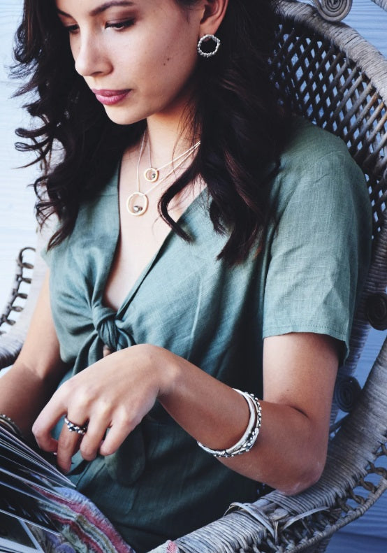 Person reading wearing two of the Keshi Pearl Circle Pendant by Tarn Contemporary Jewellery